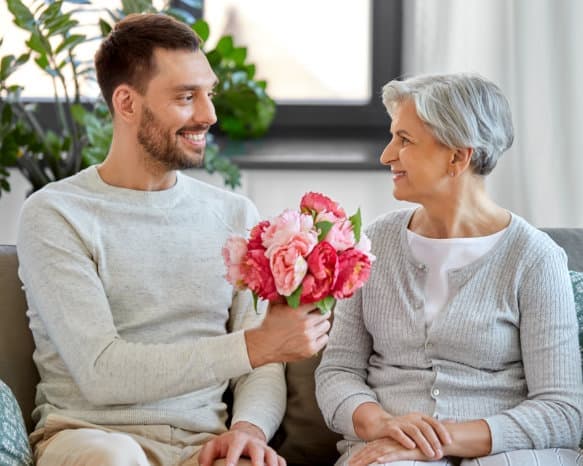 male caregiver giving flowers to the senior woman