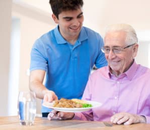 male caregiver giving food the the senior man