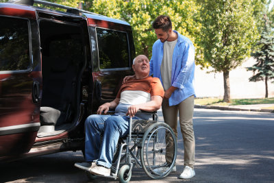caregiver assisting senior man get on the van