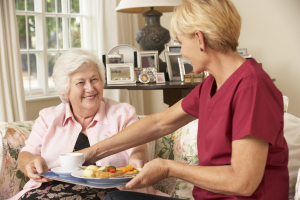 caregiver giving food to senior woman